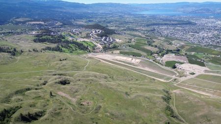 An aerial view of grasslands on the eastern slopes of Kelowna, with agricultural and urban development sprawling out below towards the shores of Okanagan Lake