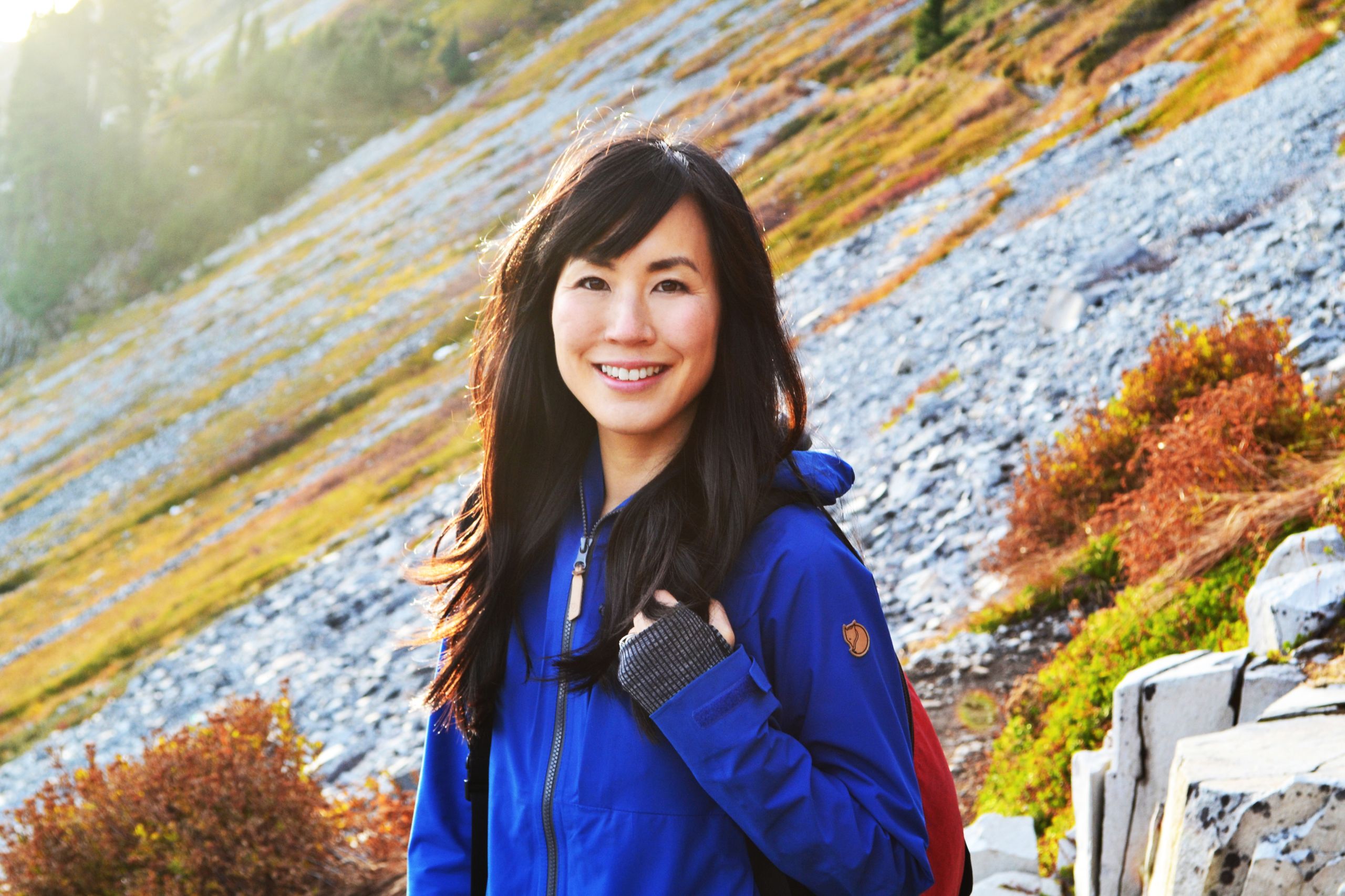 A photo of Dr. Melissa Lem wearing a blue jacket on a mountain slope
