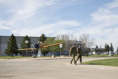 Two military personnel in uniform walk past a plane on display