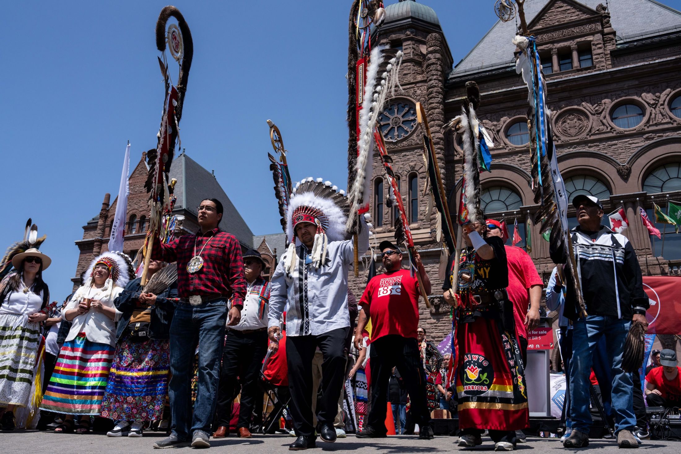 First Nations leaders wearing traditional regalia stand outside the Ontario legislature during a rally.