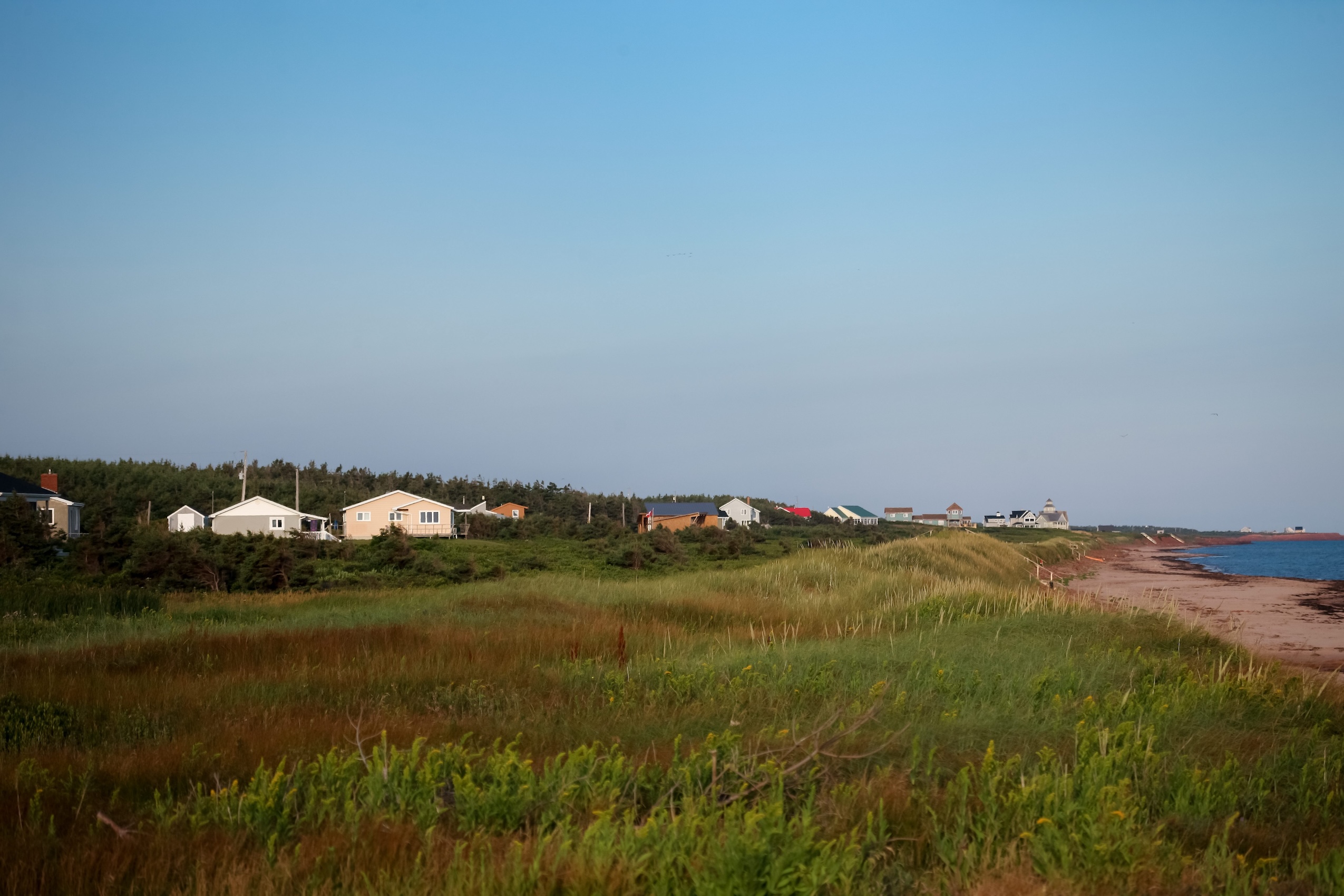 Colourful houses line a grassy shoreline in Cavendish, Prince Edward Island.