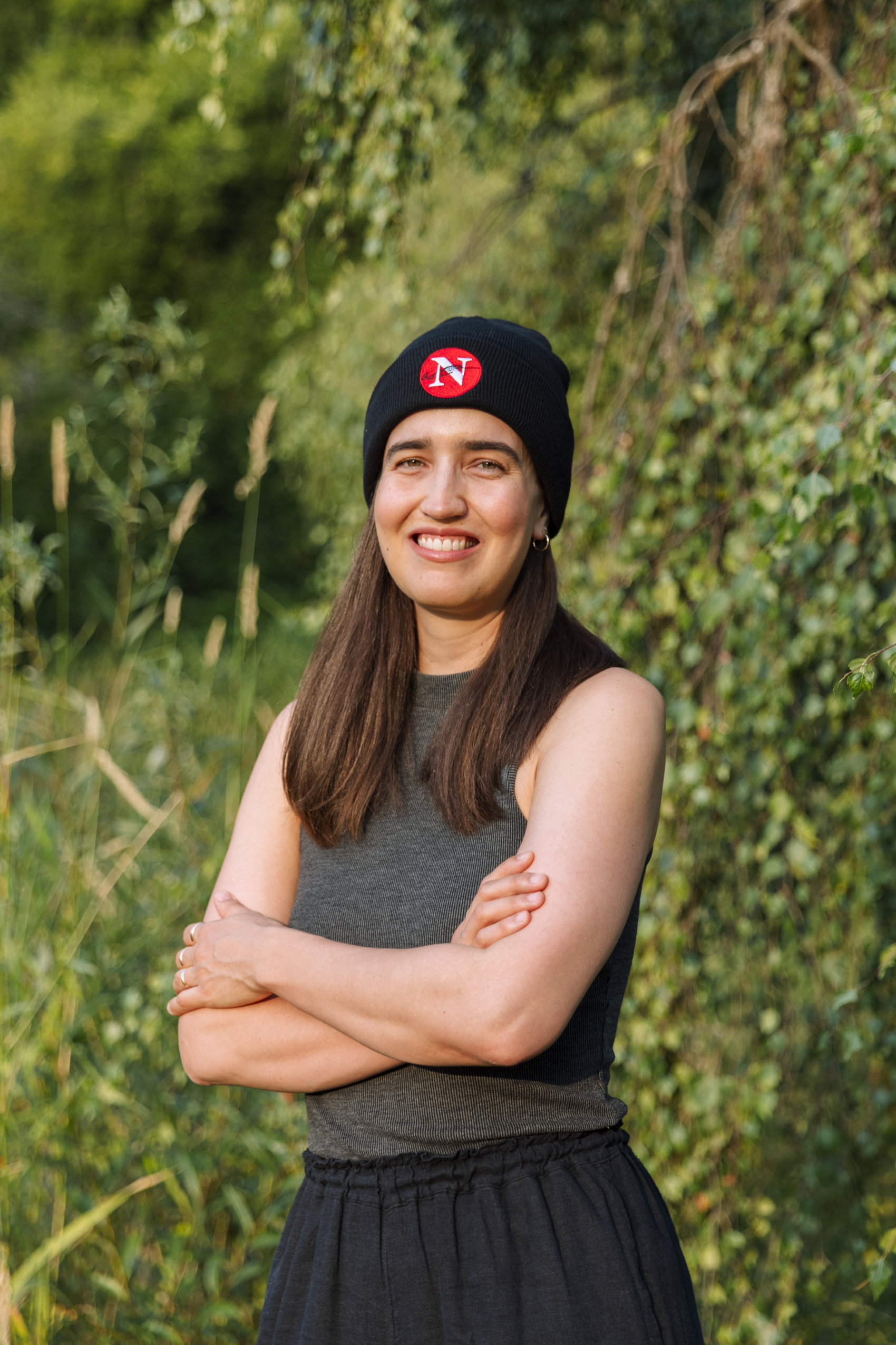One of The Narwhal's new assistant editors, Paloma Pacheco, is seen standing among some trees and wearing a Narwhal touque.