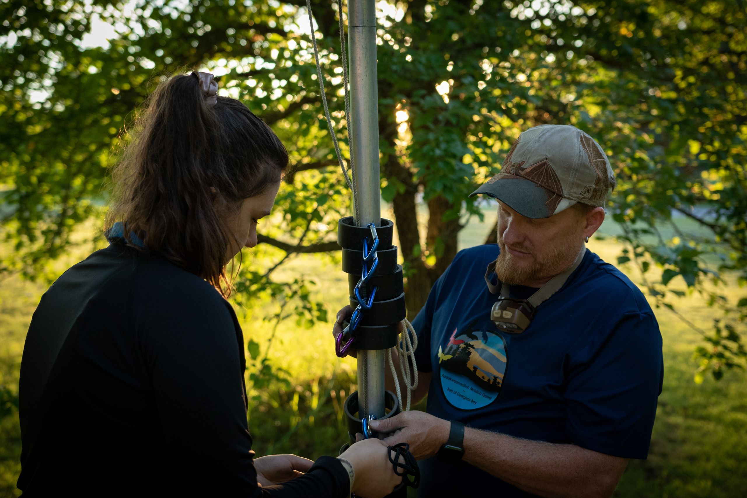Bat researcher Derek Morningstar being helped by a woman to set up a bat trapping net.