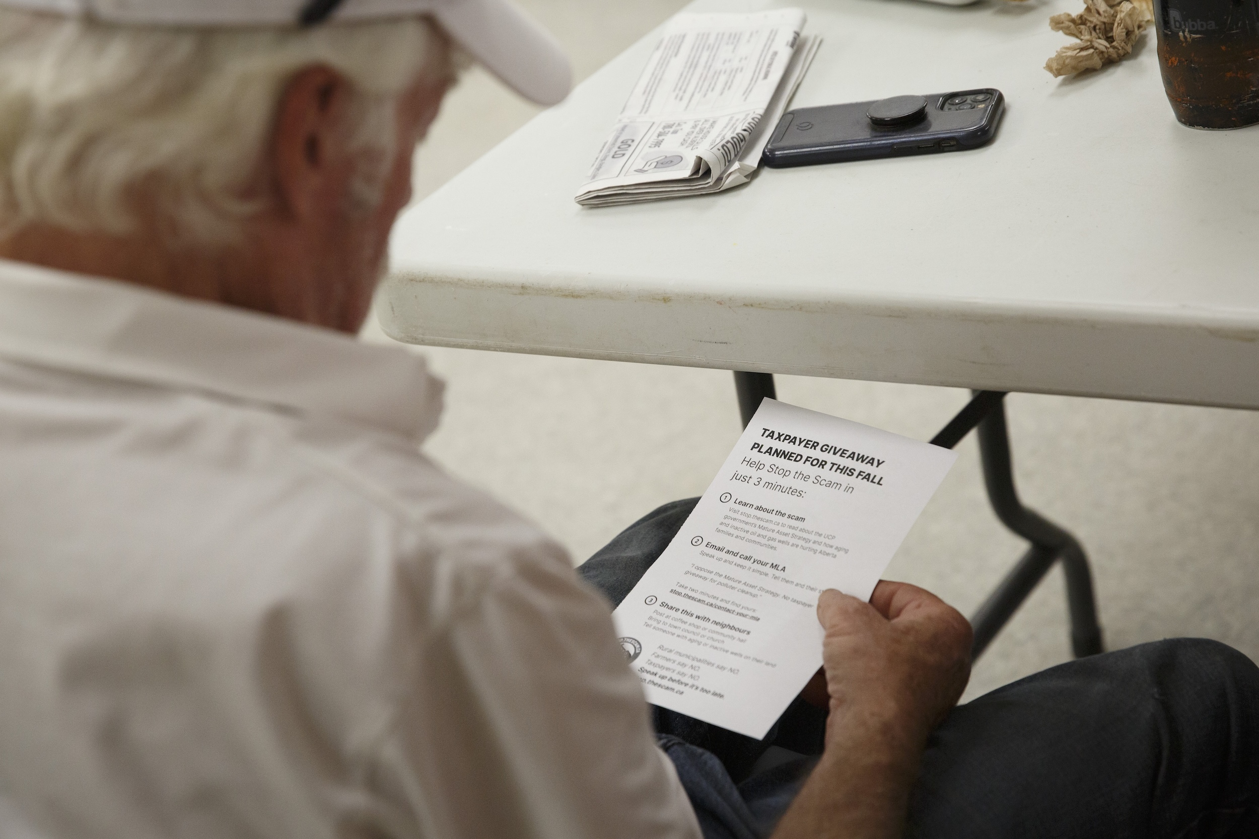 A man looking at a taxpayer pamplet at a surface rights meeting in Warburg, Alta in September 2025