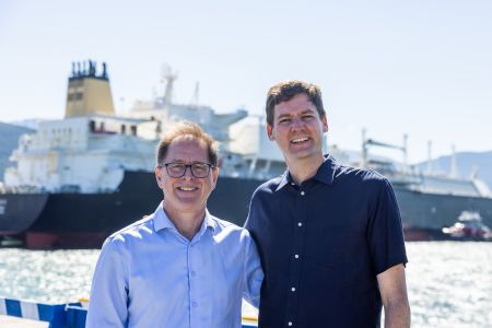 BC Energy Minister Adrian Dix and Premier David Eby stand side by side in front of an LNG carrier ship