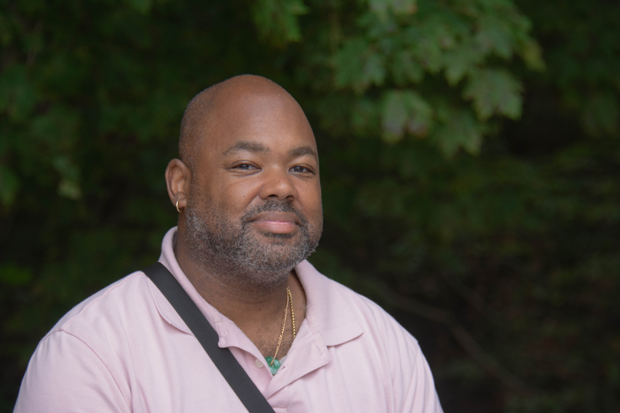 A man poses for a photo in Halifax's Point Pleasant Park with greenery in the background.