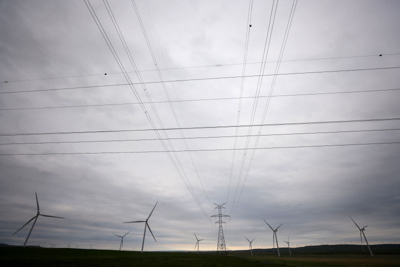Power transmission lines and wind turbines are silhouetted against a big Alberta sky near Pincher Creek.