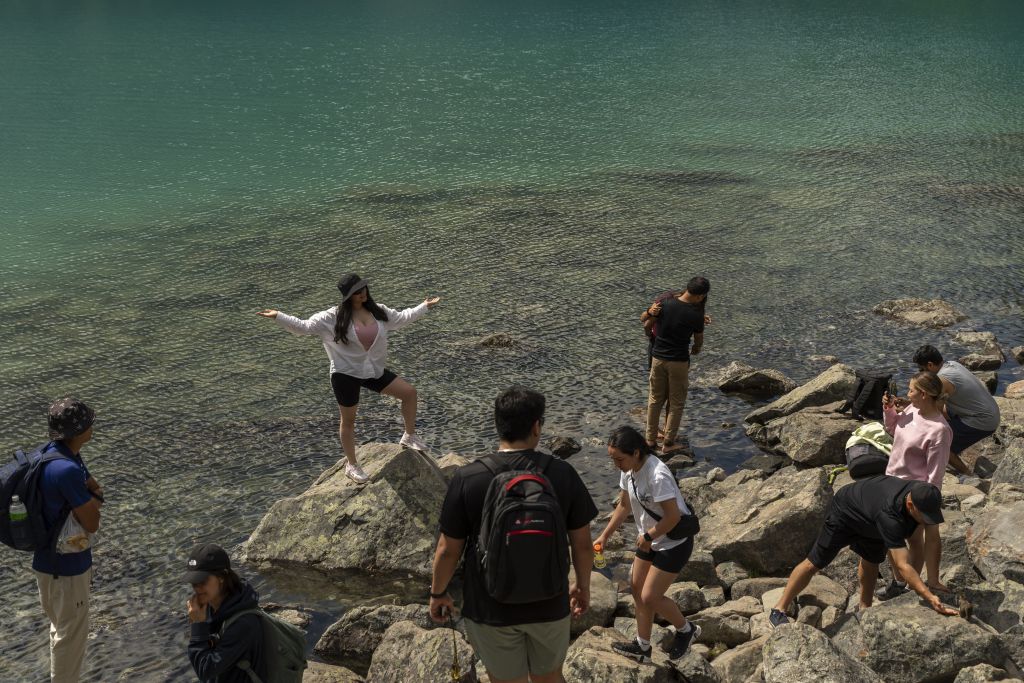 Hikers pose for photos at the water's edge at Joffre Lakes.