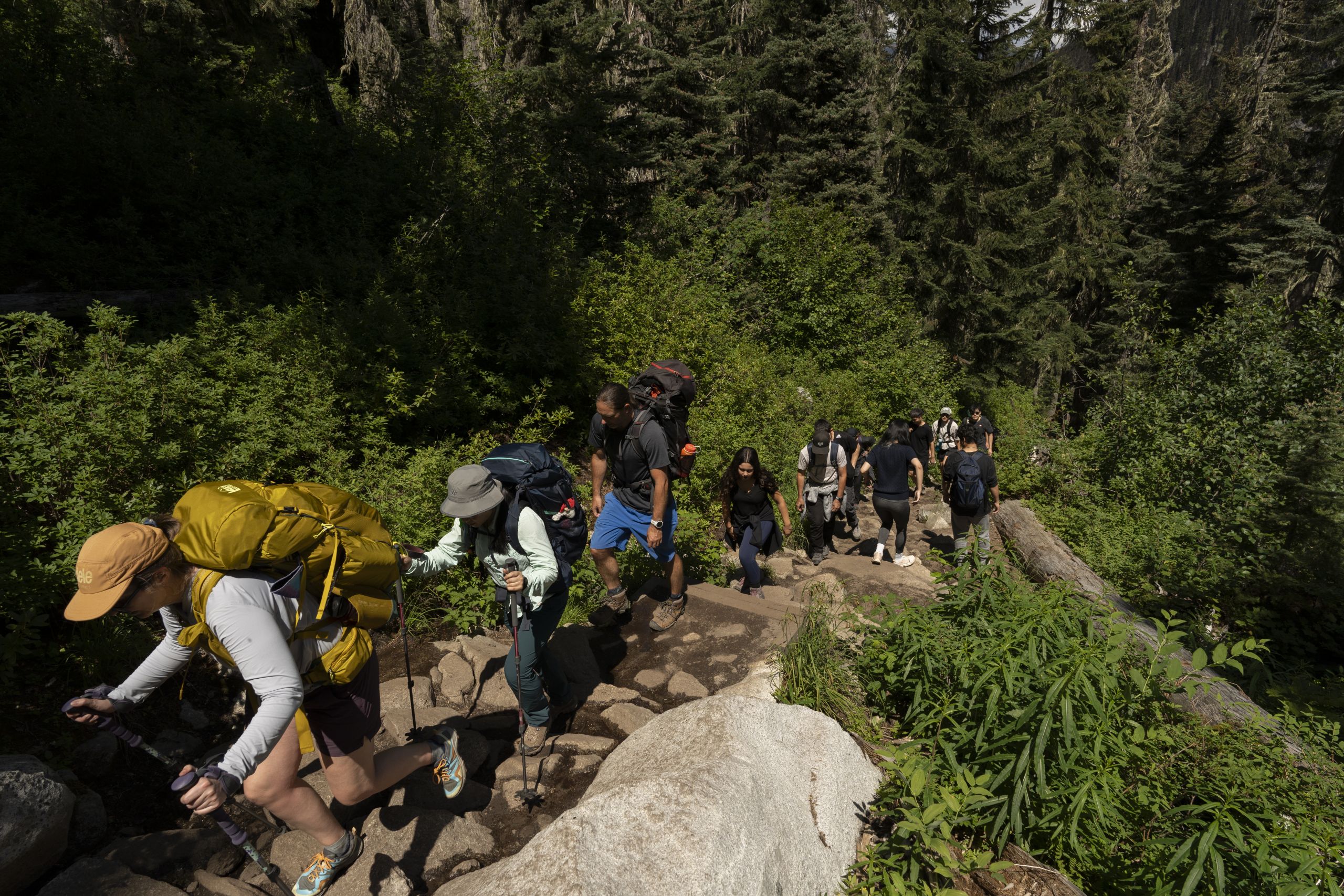 At Joffre Lakes, the path is crowded with people. The trail is exposed under the sun, and people walk directly behind each other like a queue up a steep incline.