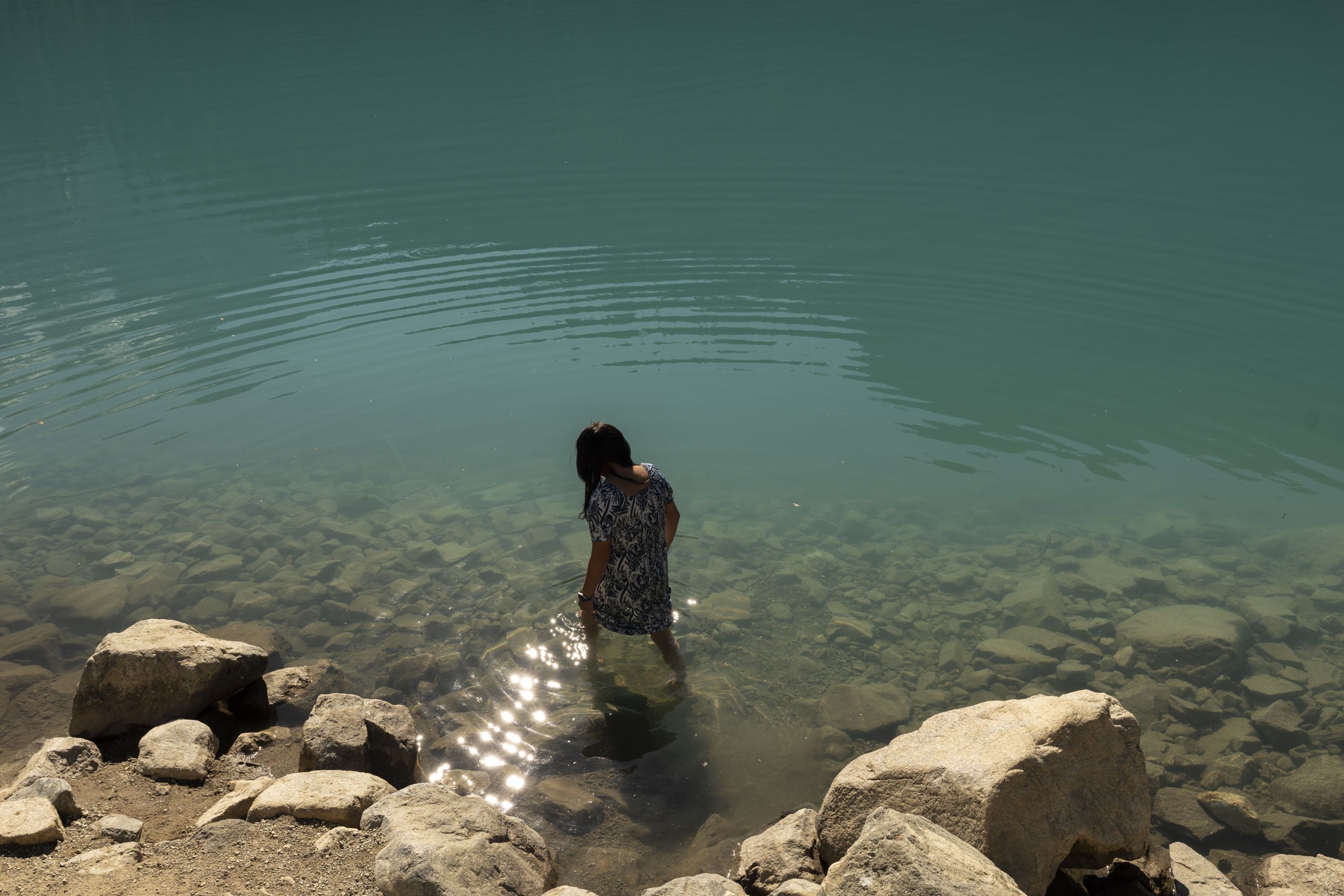 Keisha Andrew walks into the turquoise glacial water at Middle Joffre Lake / Pipi7íyekw.