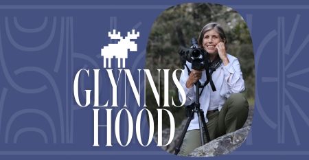 A headshot of Glynnis Hood kneeling behind a camera and tripod, nestled in a purple banner with her name and a moose icon overlaid in white