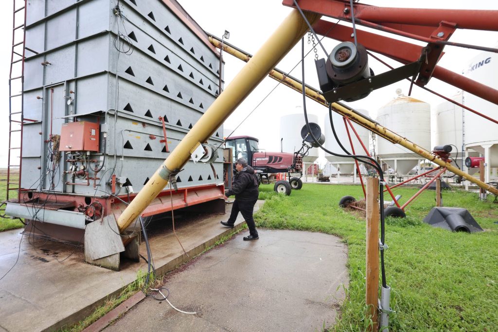 A man walks under some farming equipment.
