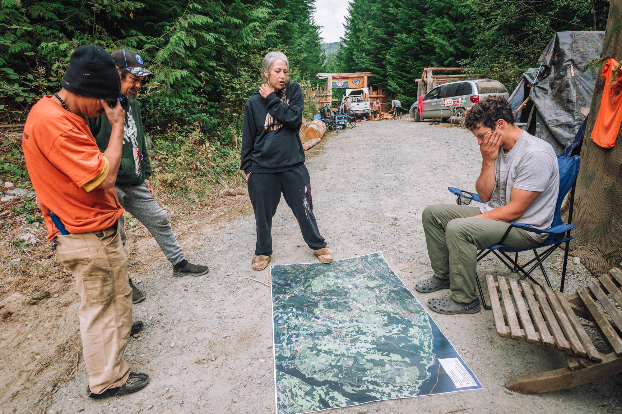 A group of people at the Walbran logging blockage gather around a map laid out on a gravel road