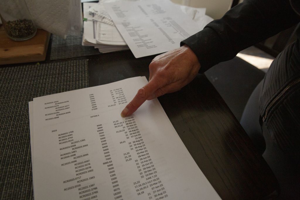 Close-up on a woman's hand pointing at numbers on a printed sheet of paper.