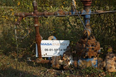 Rusted oil well piping with a sign at the bottom reading "MAGA Energy."