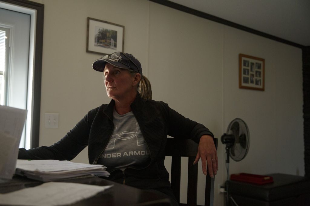 A woman sitting at a desk in a dark room, looking at a computer.