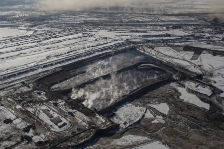 Steaming grey ponds set against a snowy earthen landscape