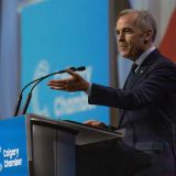 Mark Carney gesturing to a crowd at a podium.