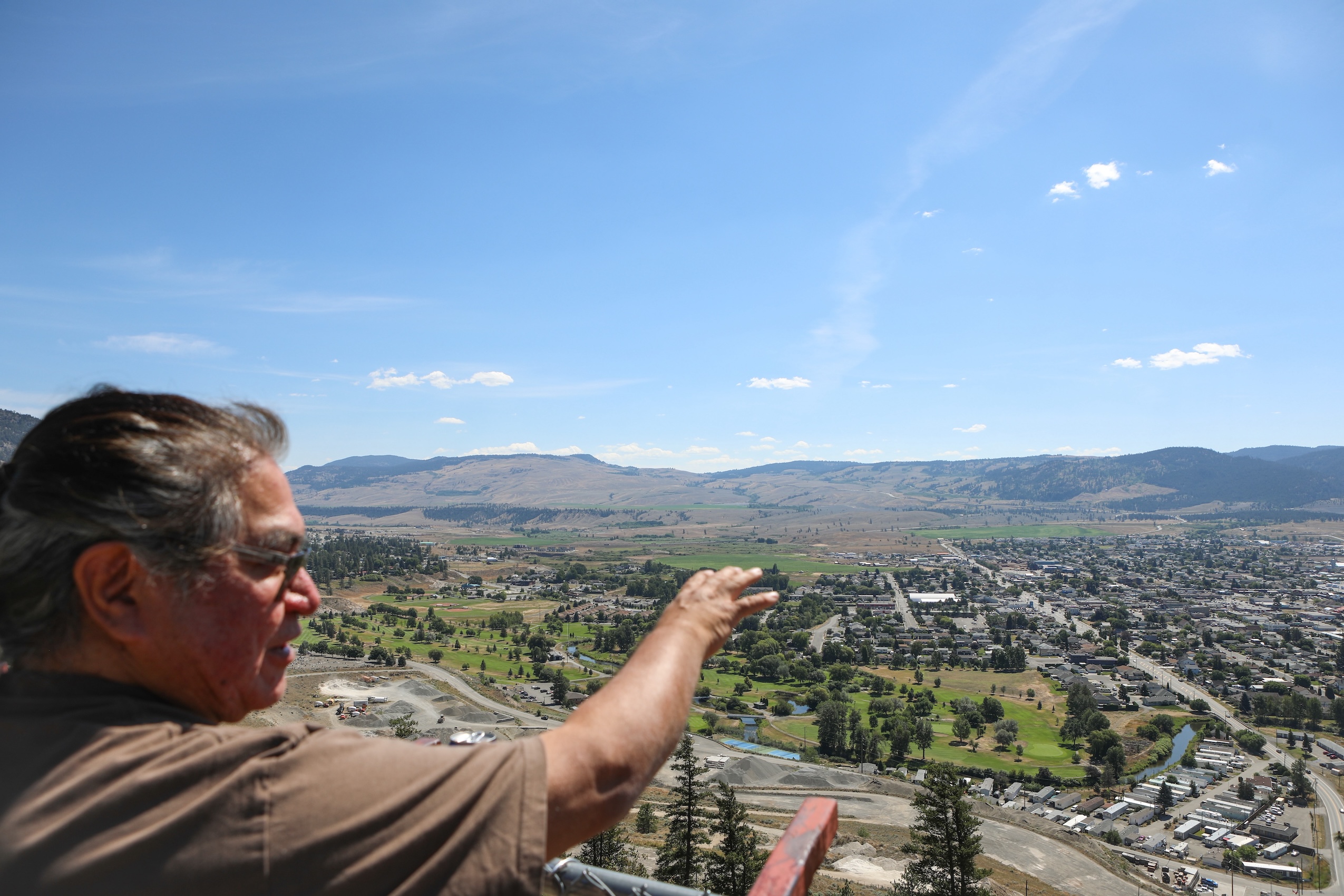 Joe Gilchrist points towards the city of Merritt, viewed from afar.