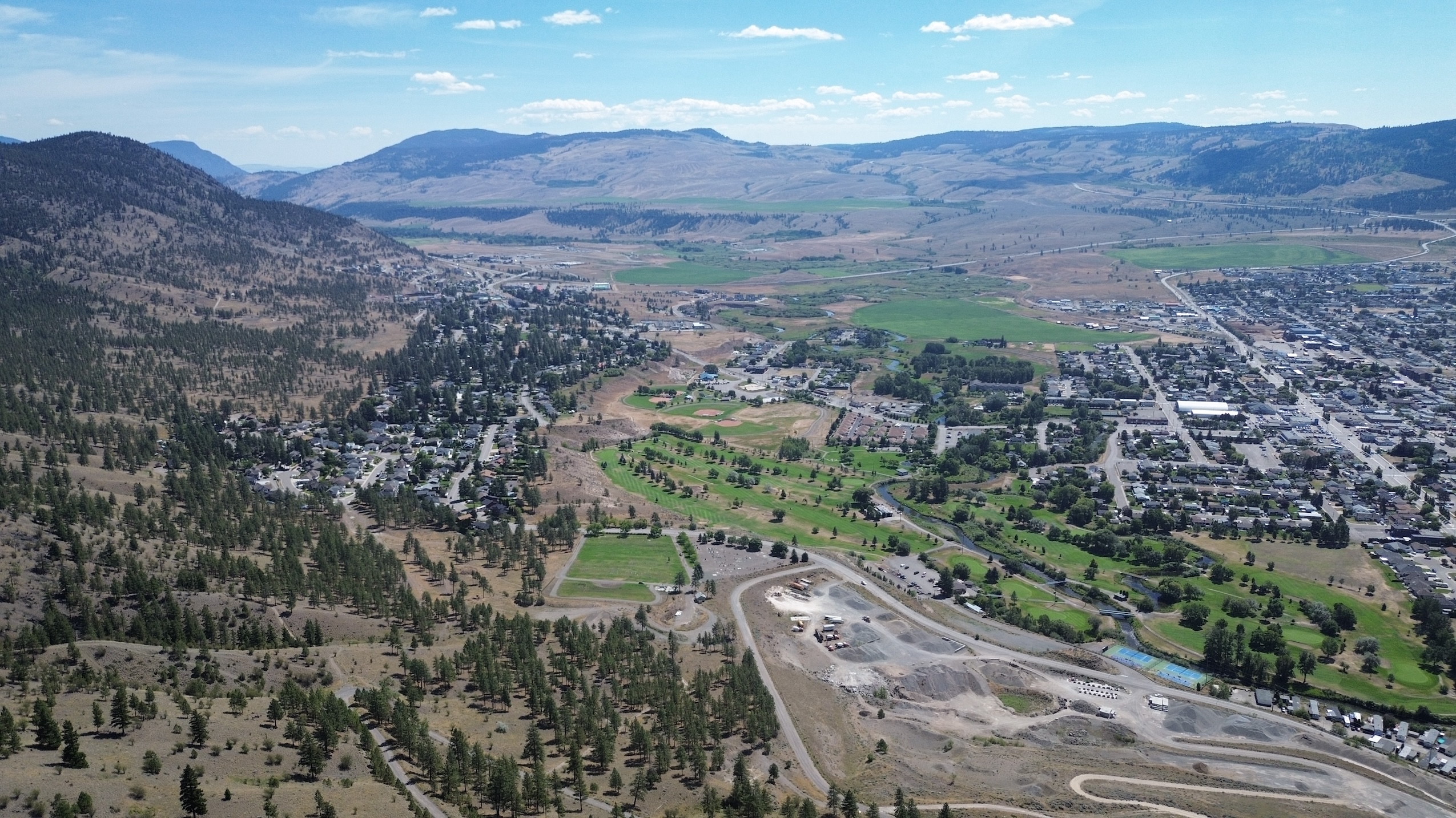 An aerial view over the city of Merritt, with a forested hillside that has undergone a prescribed burn.