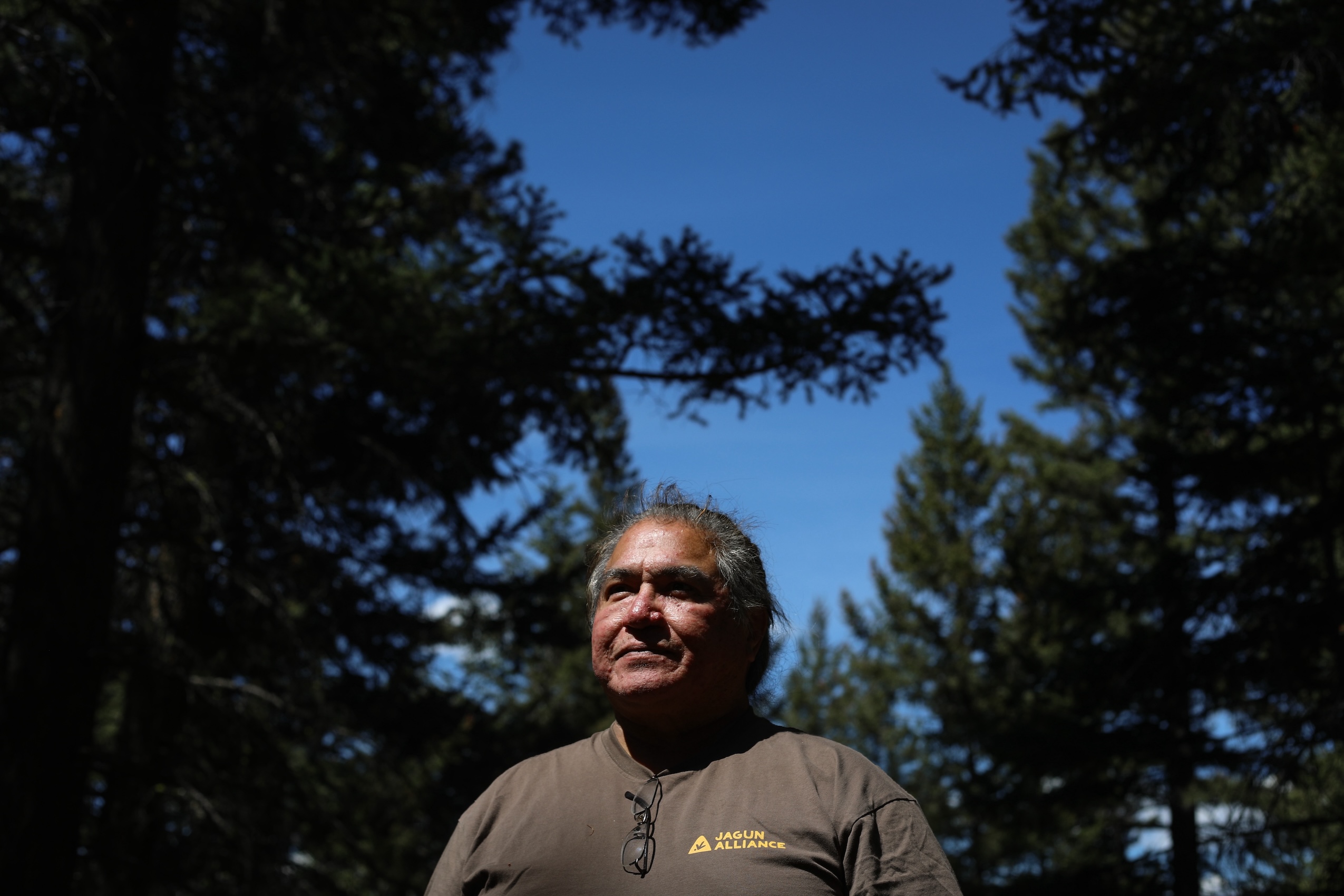 Joe Gilchrist, a Secwépemc Nation firekeeper, stands at a forest's edge.