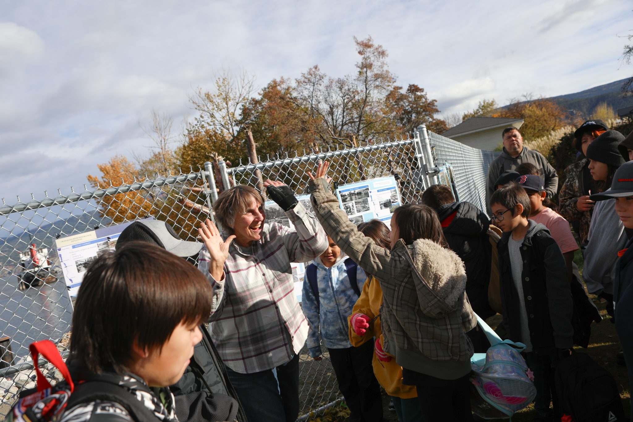 A woman gives high fives to a group of school children.