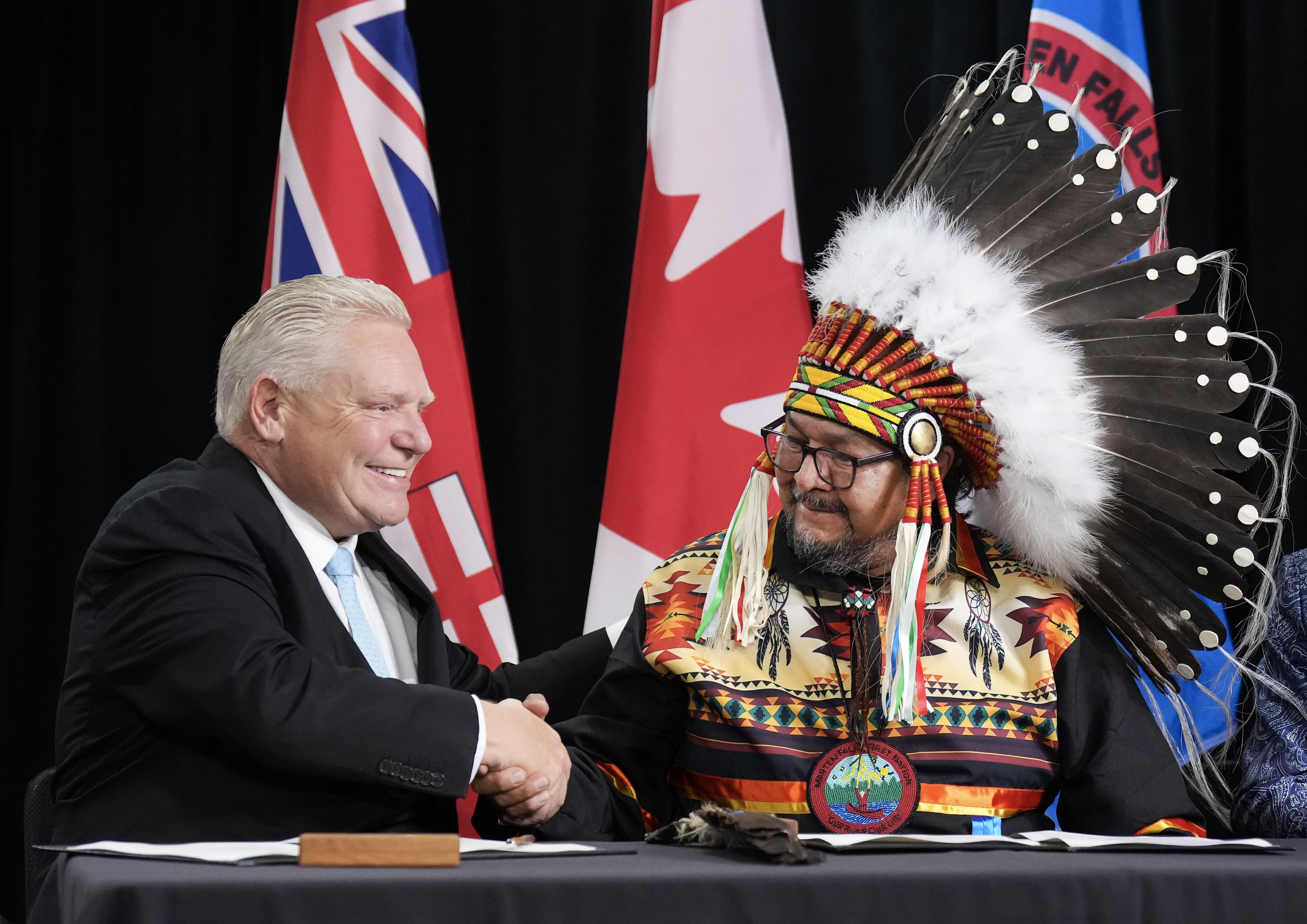 Ontario Premier Doug Ford and Marten Falls First Nation Bruce Achneepineskum shake hands at a table.