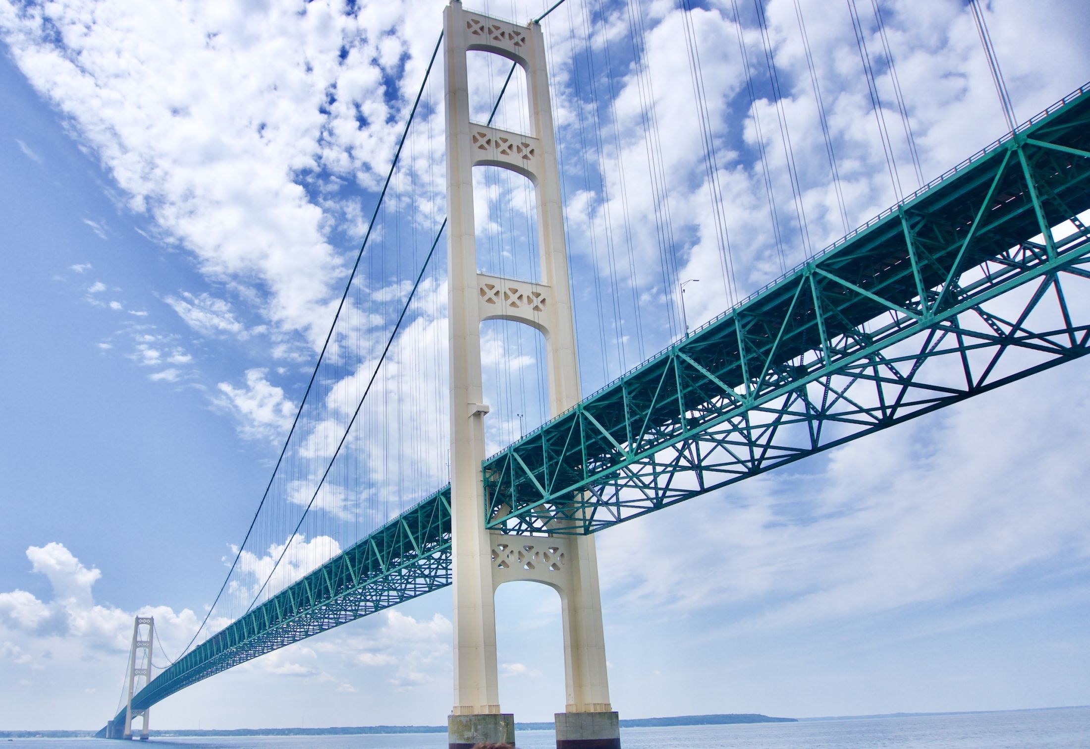 Michigan's Mackinac Bridge stands against a blue sky with clouds.