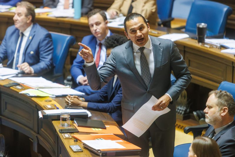Manitoba Premier Wab Kinew stands and speaks emphatically in the provincial legislature with MLAs seated around him.