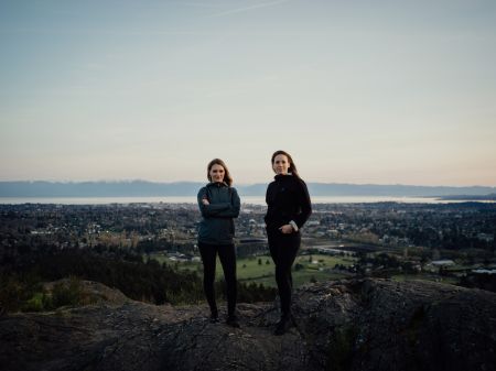 Emma Gilchrist and Carol Linnitt stand on a rocky ledge overlooking Victoria, B.C.