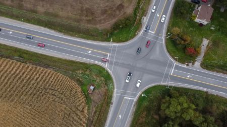 An aerial view of an intersection with cars driving across it.
