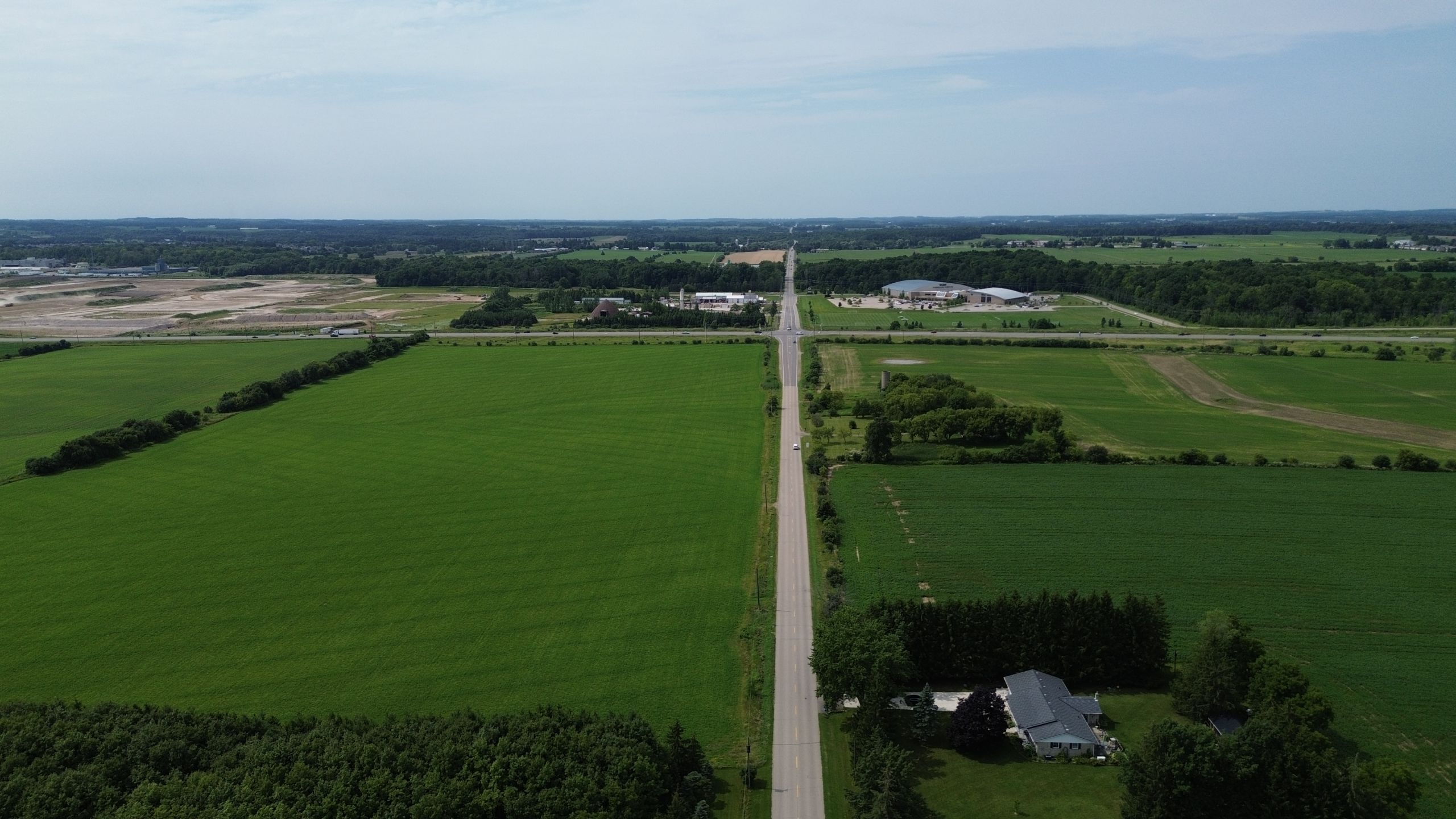 An aerial view of a road cuts through green farmland.