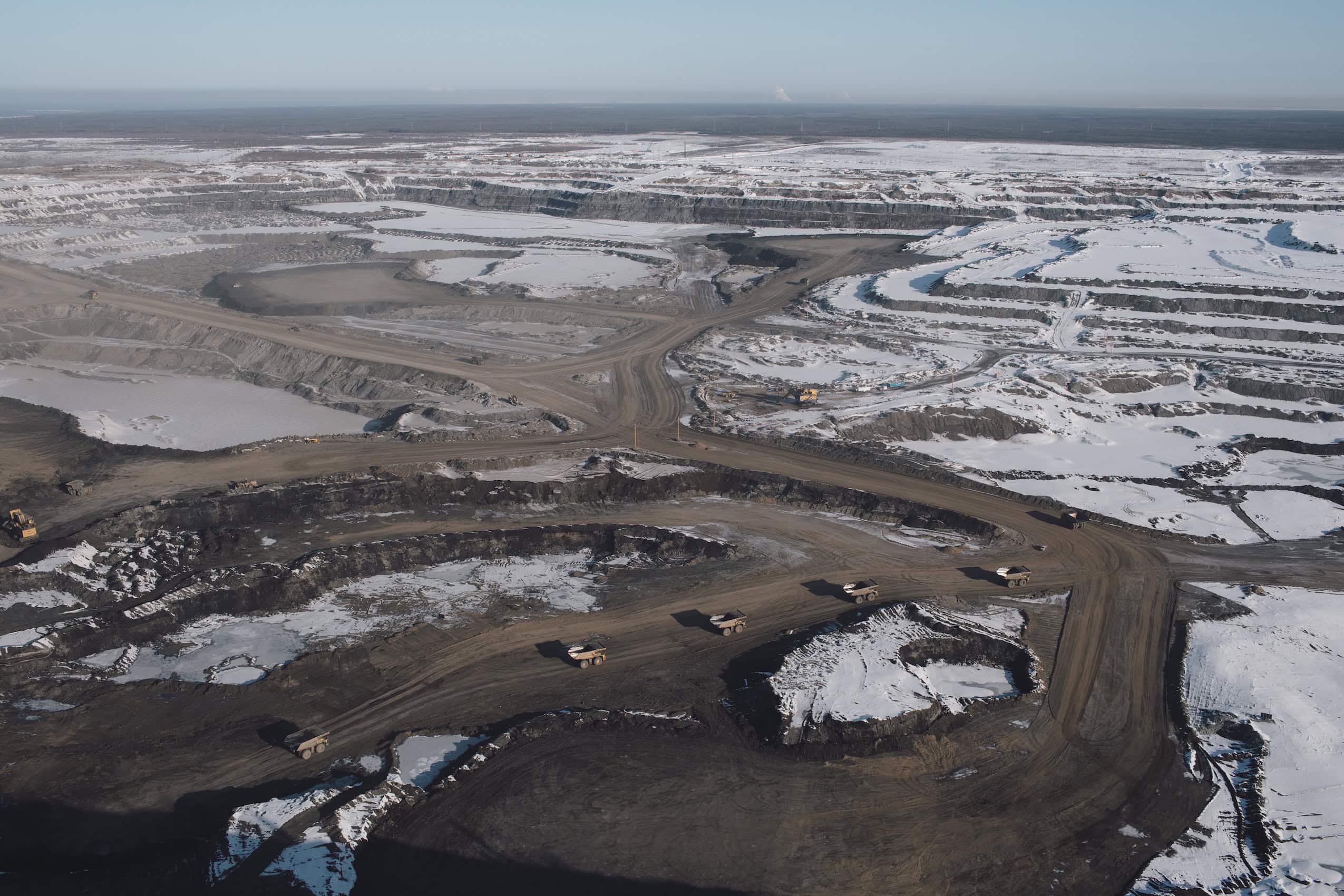 An aerial view of an open-pit oilsands mine near Fort McMurray, Alta, partly covered in snow.