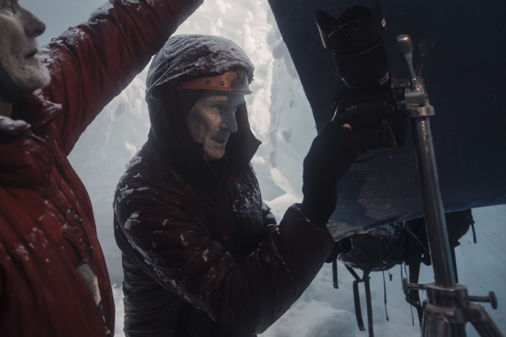 A man focuses on a camera inside of a glacier