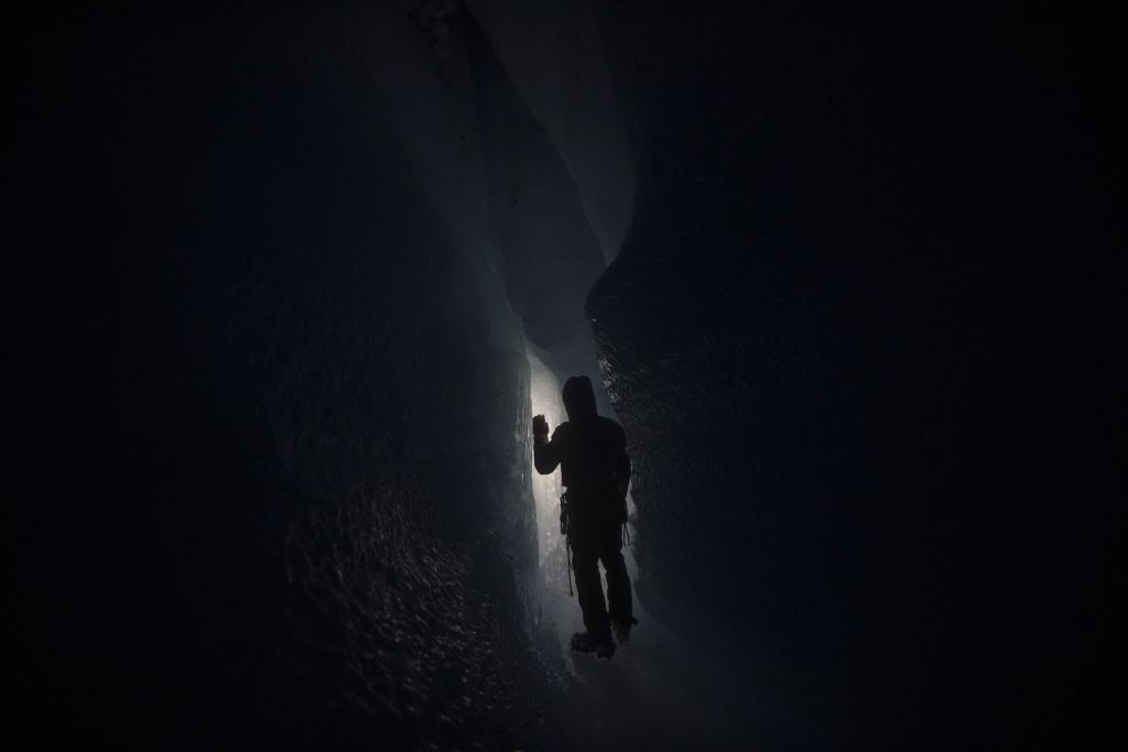 The dark narrow walls of a glacier with a person in the centre