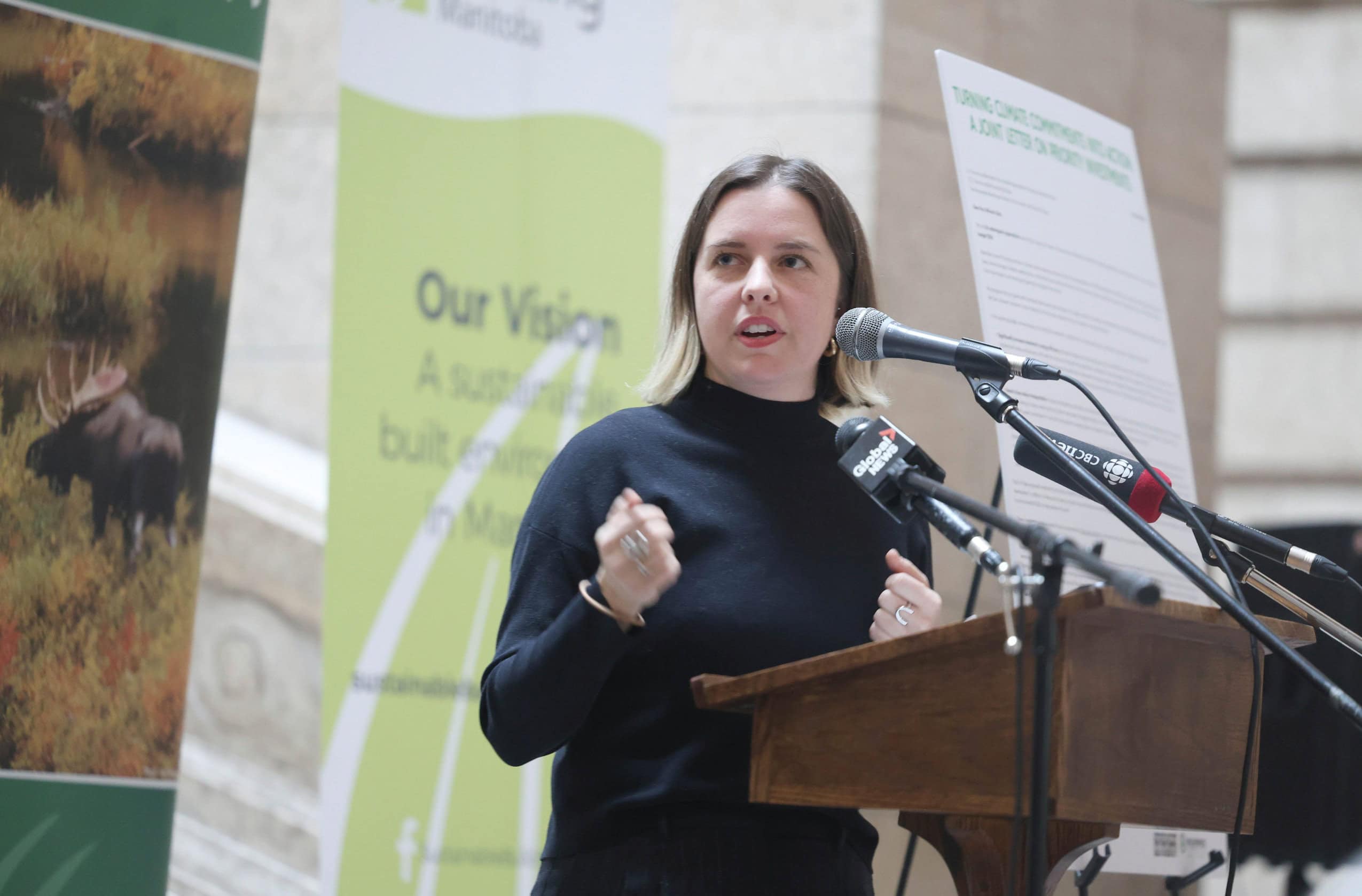 Laura Cameron speaks into microphones at a press conference about climate action in Winnipeg, Manitoba.