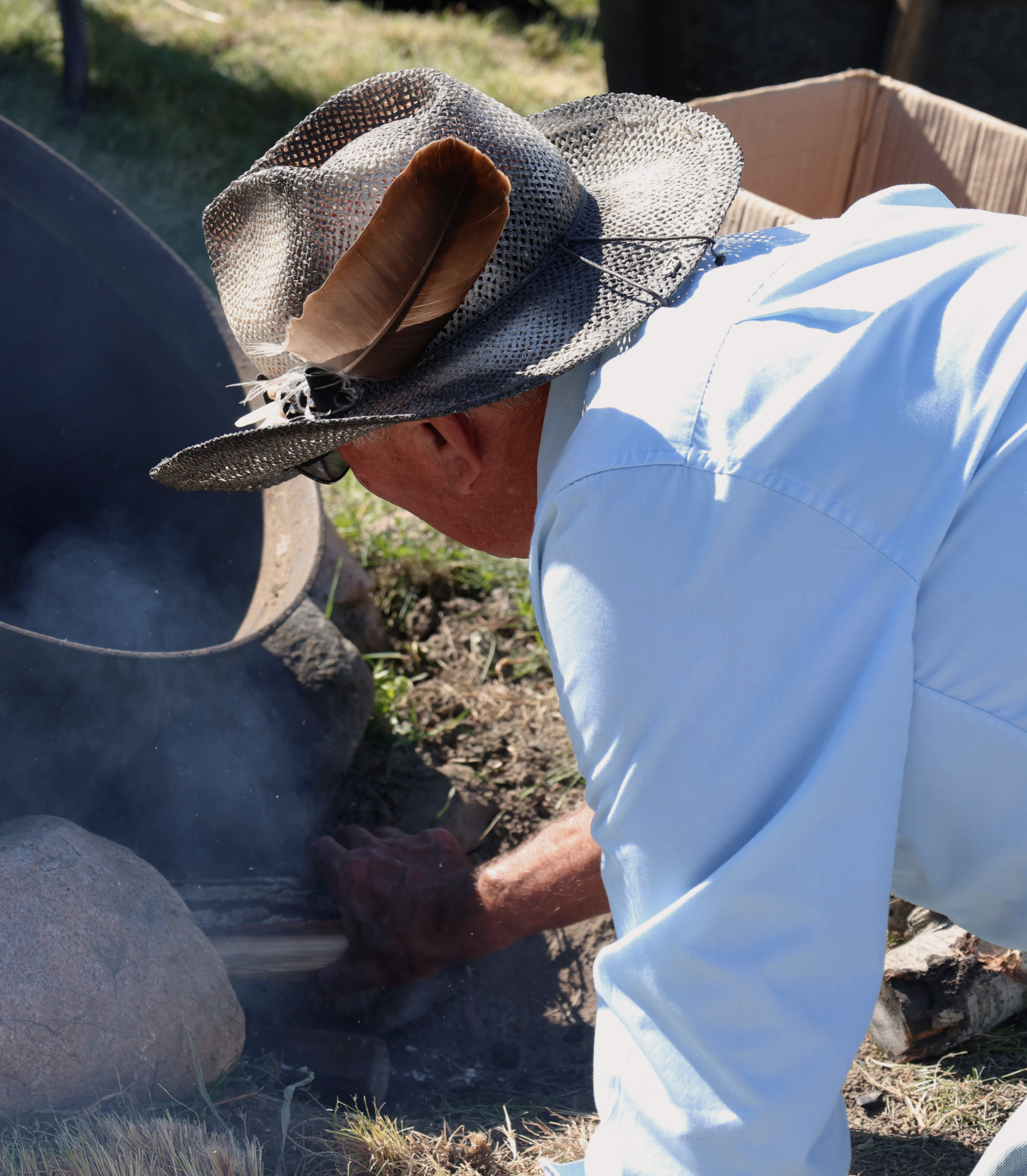 Jeff Beaver bends over the fire pit to fix some of the wood during the wild rice processing workshop for the Alderville Black Oak Savanna’s 2025 Prairie Day on October 3, 2025.