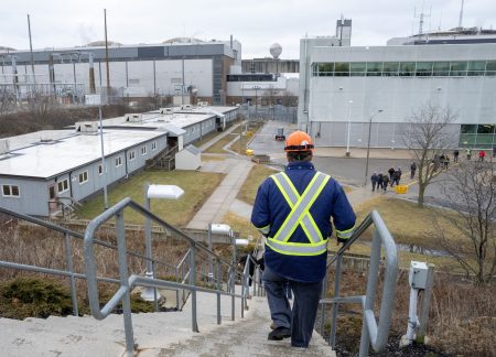 Seen from behind, a worker walks down a flight of stairs toward the Pickering Nuclear Generating Station in Ontario.