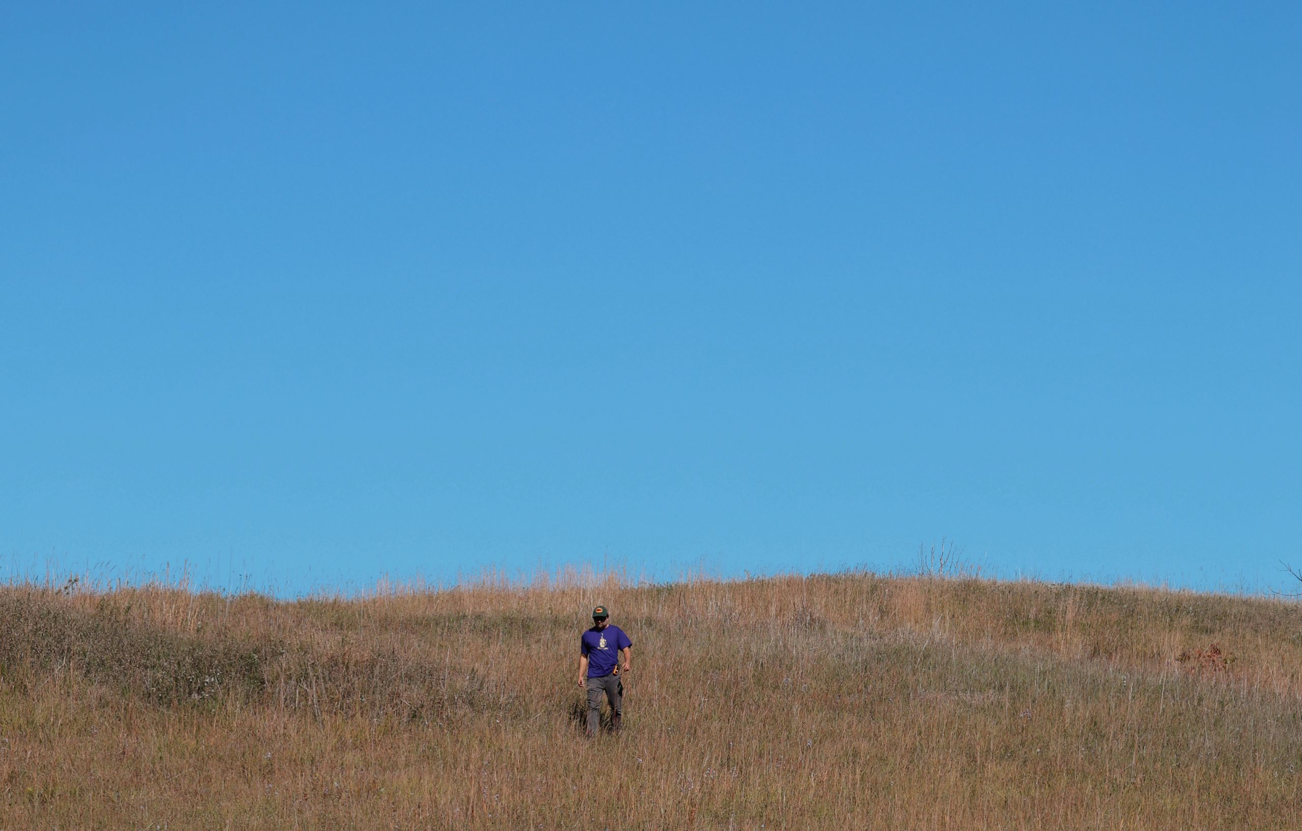 Radek Odolczyk walking down a hill of tallgrass at the Alderville Black Oak Savanna during Prairie Day on October 3, 2025.