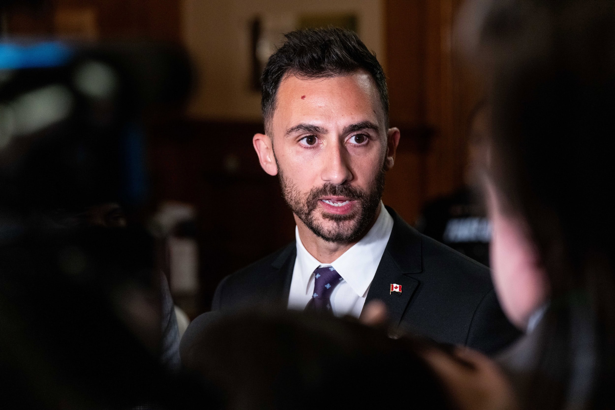 A close-up of Stephen Lecce, a thin man with a beard wearing a black suit with a Canada pin on the lapel