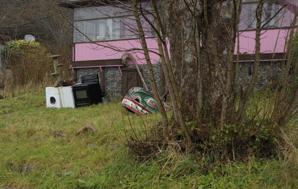 ‘Na̱mg̱is carved whale head in the front yard of a pink house