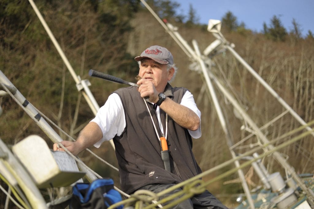 Lorne Smith, a ‘Na̱mg̱is clam-digger, points with the hilt of a hammer