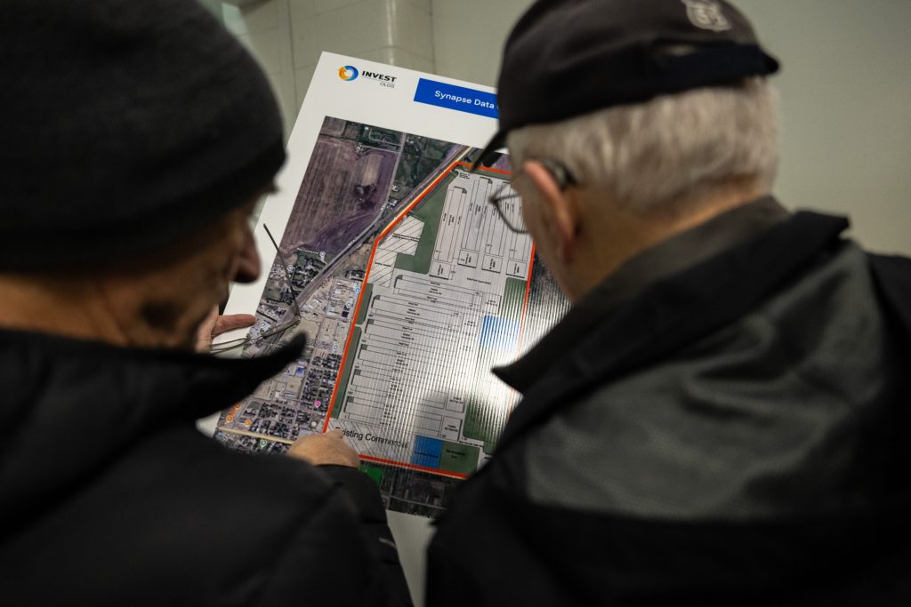 Two residents of Olds, Alta., review a plan for a proposed data centre in the community.