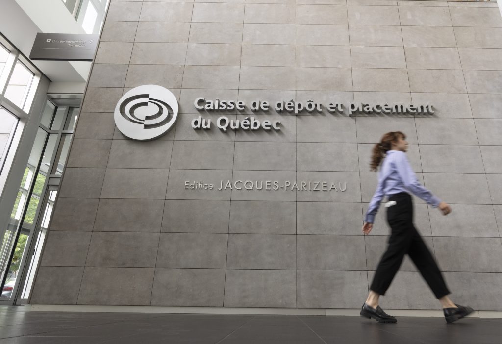A person walks by a sign that reads "Caisse de dépot et placement du Québec" in the lobby of an office building in downtown Montreal.