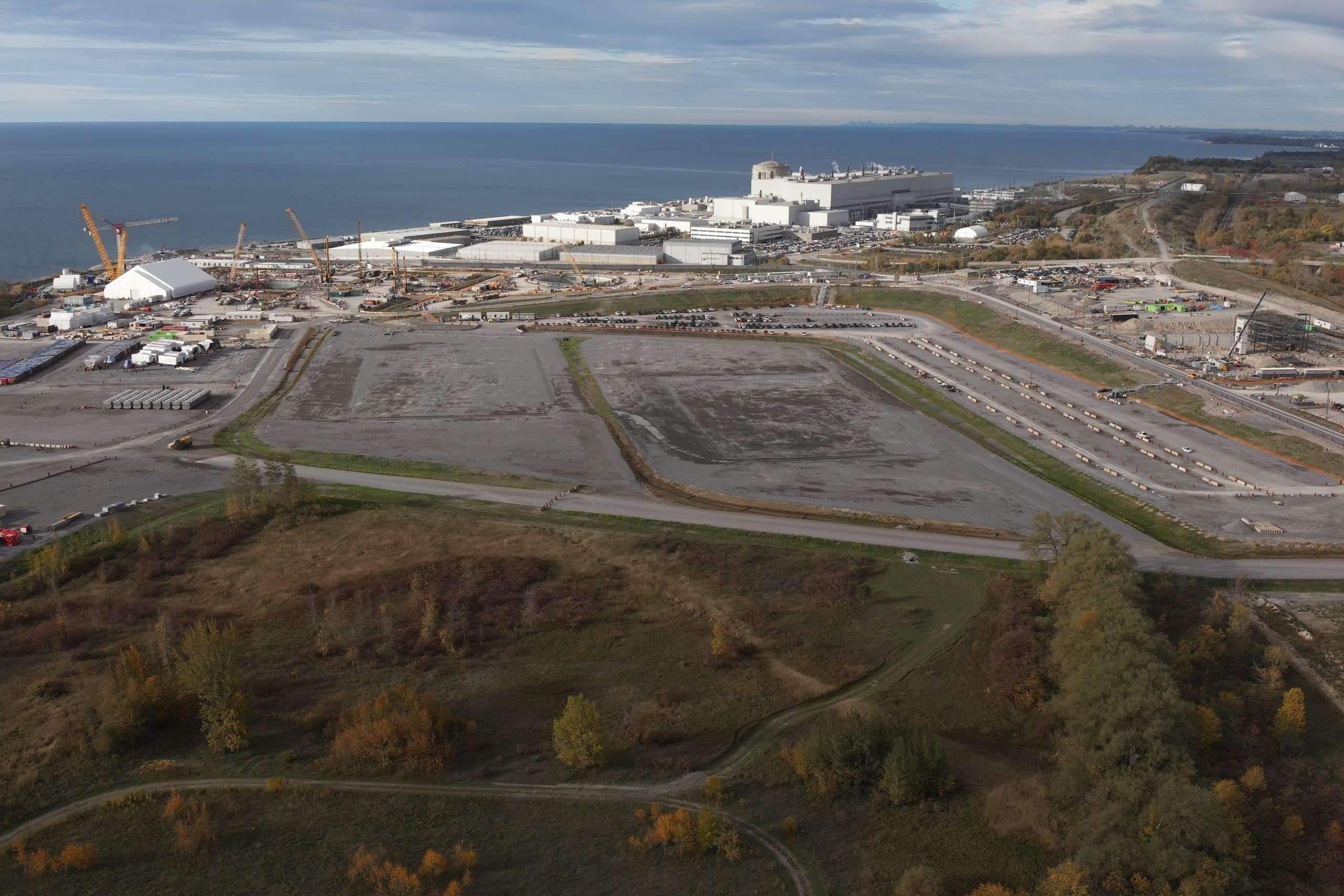 A large empty construction site next to a nuclear facility around a lake