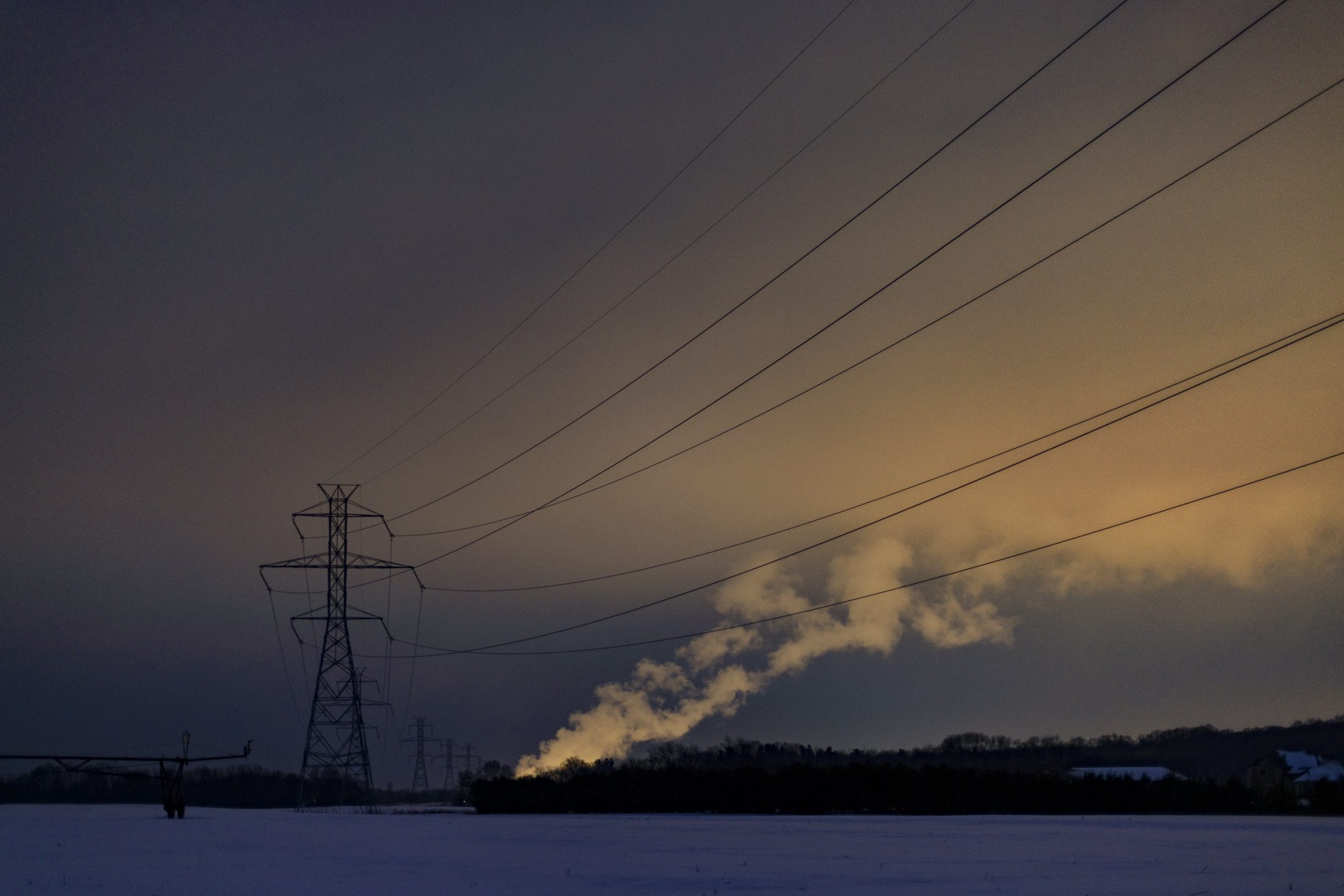 Power lines are silhouetted against a twilight sky.