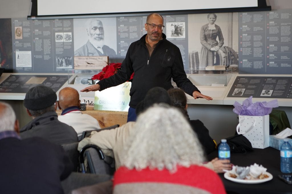 Ken Johnston speaks to a group about his Walk to Freedom retracing the Underground Railroad route from Detroit to Dresden, Ont. Behind him is a Black History display featuring a photo of Harriet Tubman and Josiah Henson, who settled in Ontario after escaping enslavement.