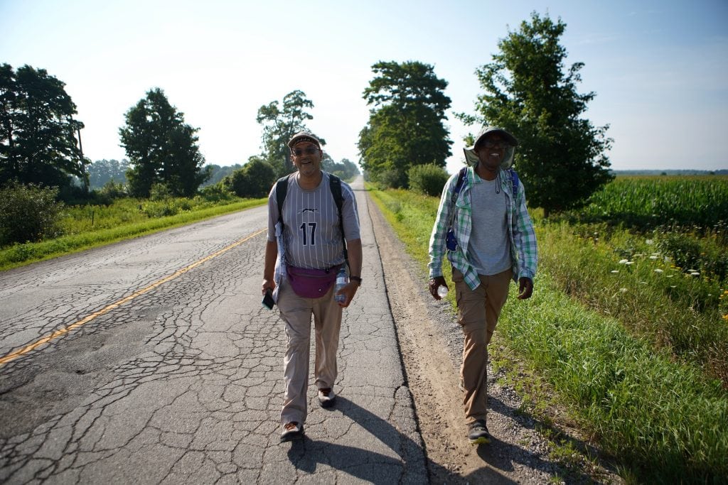 Ken Johnston (L) walks through farmland between Guelph and Fergus, Ont., alongside Zachee Nzeyimana, while retracing an Underground Railroad route from Niagara Falls to Owen Sound on his Walk to Freedom.