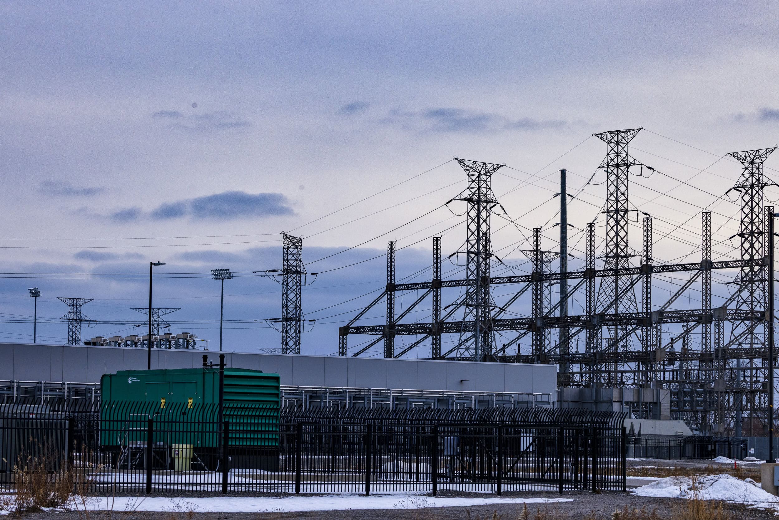 Electric cables and towers at a data centre, with a dusk-lit sky behind them.