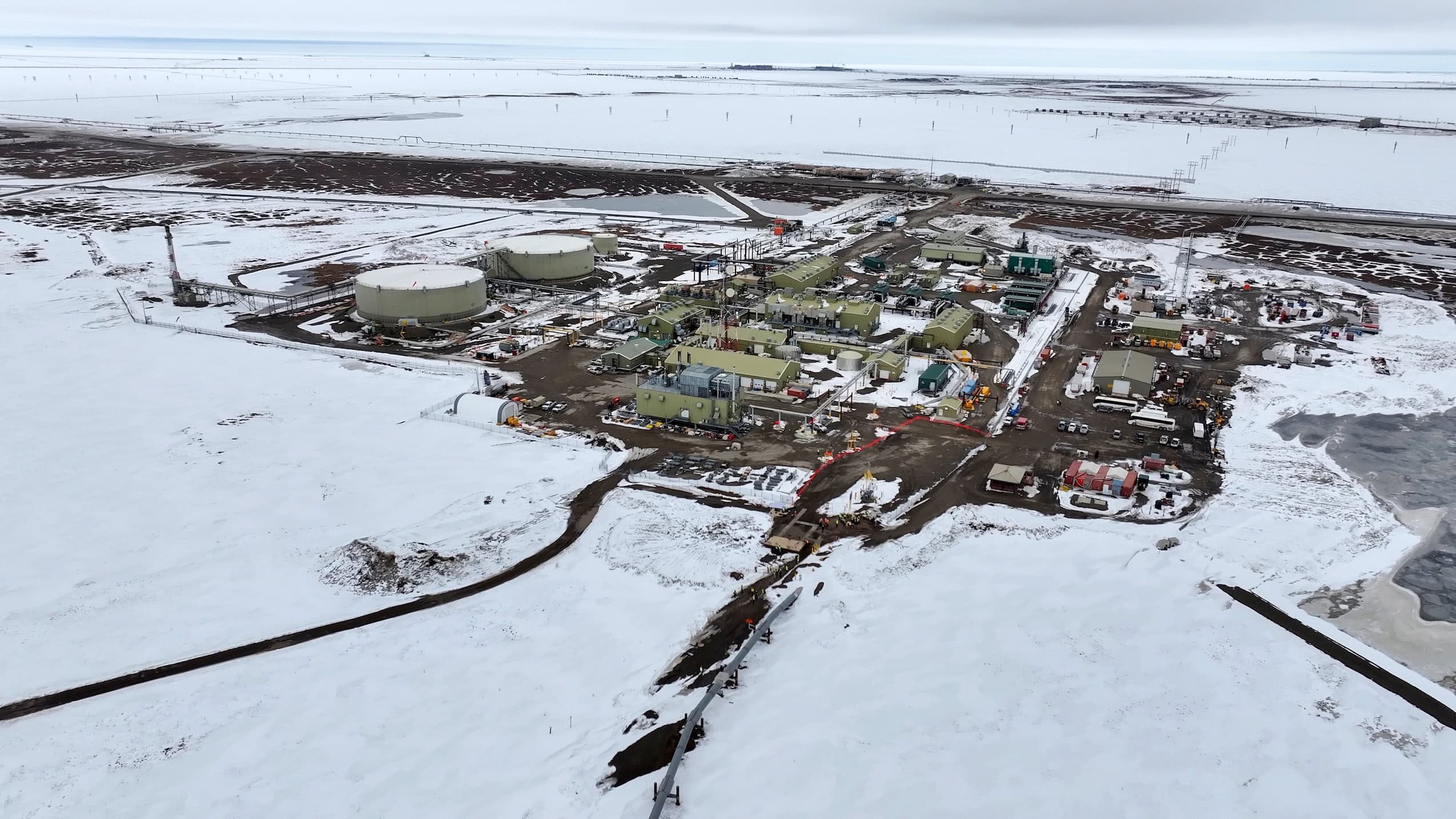 An aerial view of oil and gas infrastructure in a snowy landscape on the north coast of Alaska.
